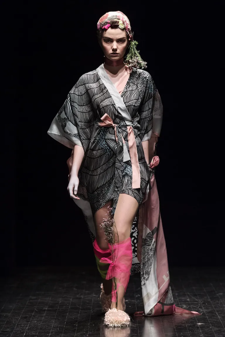 A short wrap dress in a black-and-white wave pattern, with pink ties and flowers in the hair.