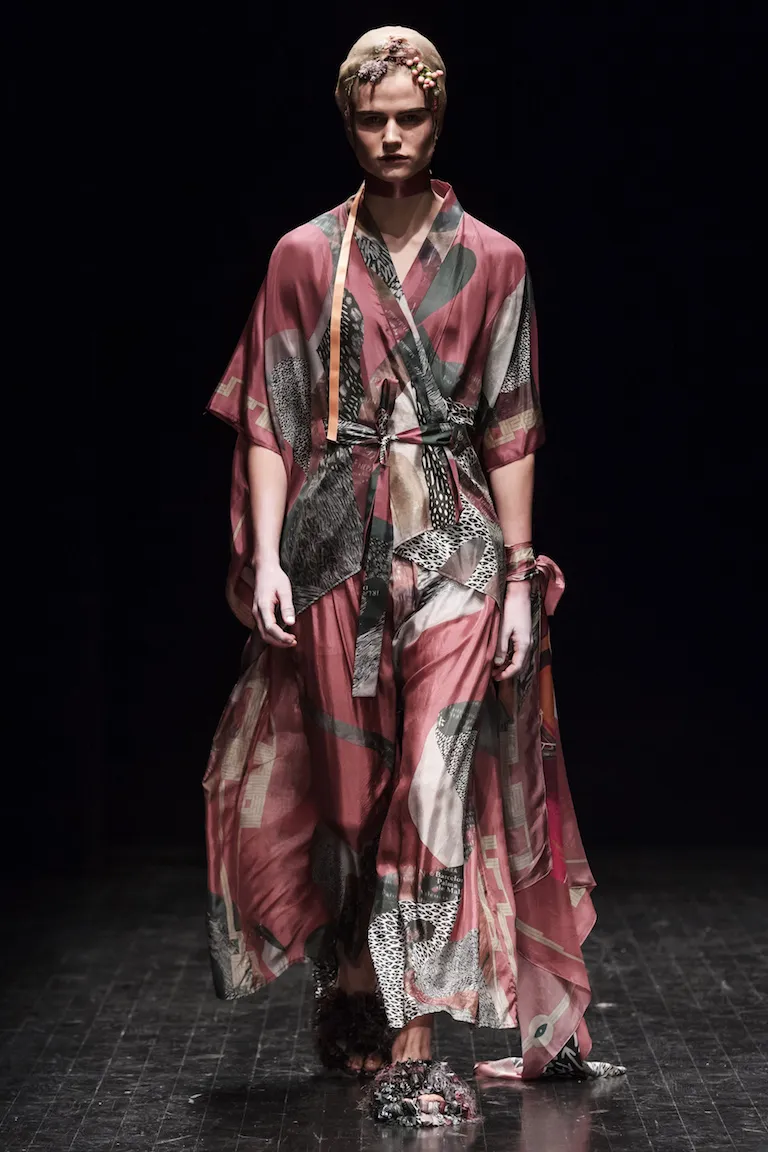 A long pink-red wrap dress with a collage of grey and black-and-white patterns and an orange ribbon.