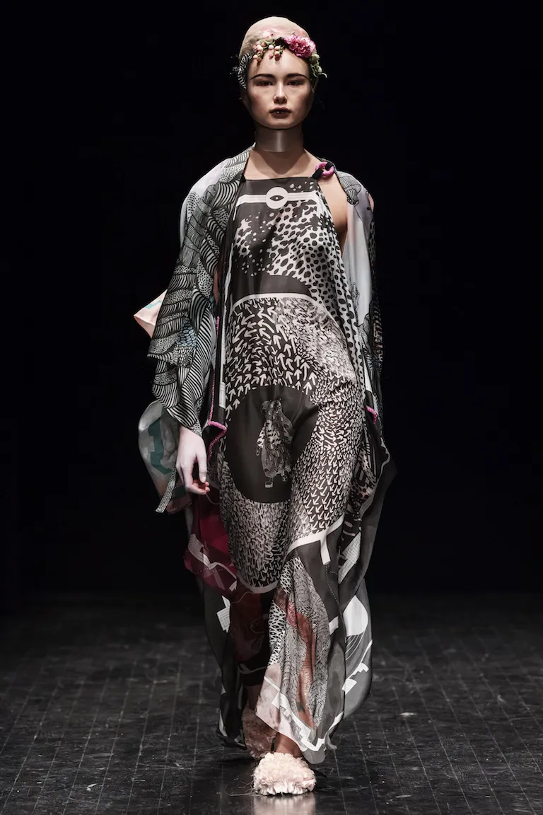 A pinafore dress and shawl in black-and-white patterns of scales, checks and small figures, with pink details.