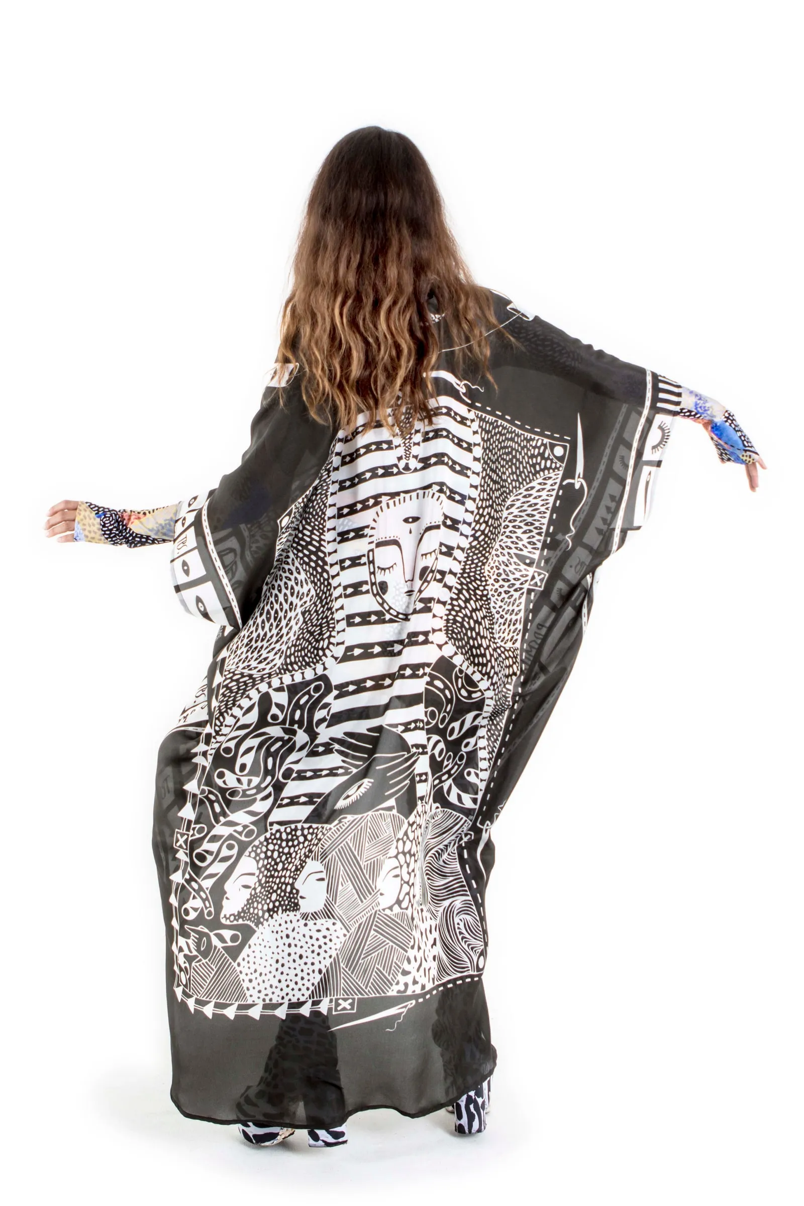 A model wearing the long Replaceable Souls kimono, seen from behind with arms outstretched to show the black-and-white print with a striped face across the back.