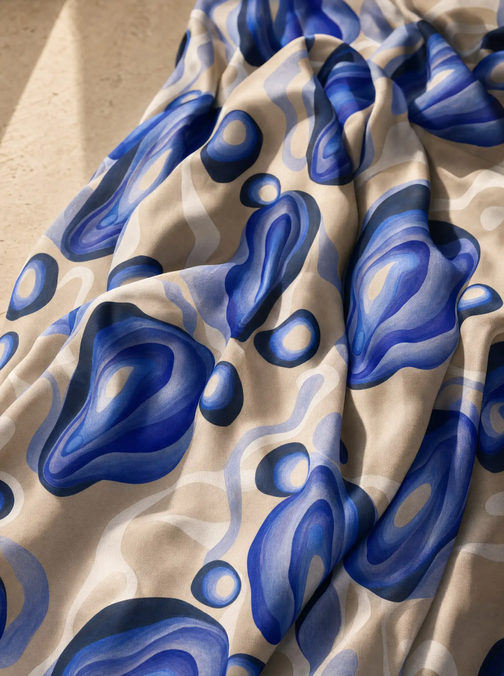A visualisation presents Homage to O’Keeffe on draped fabric, with layered blue organic forms against a sand-coloured ground.