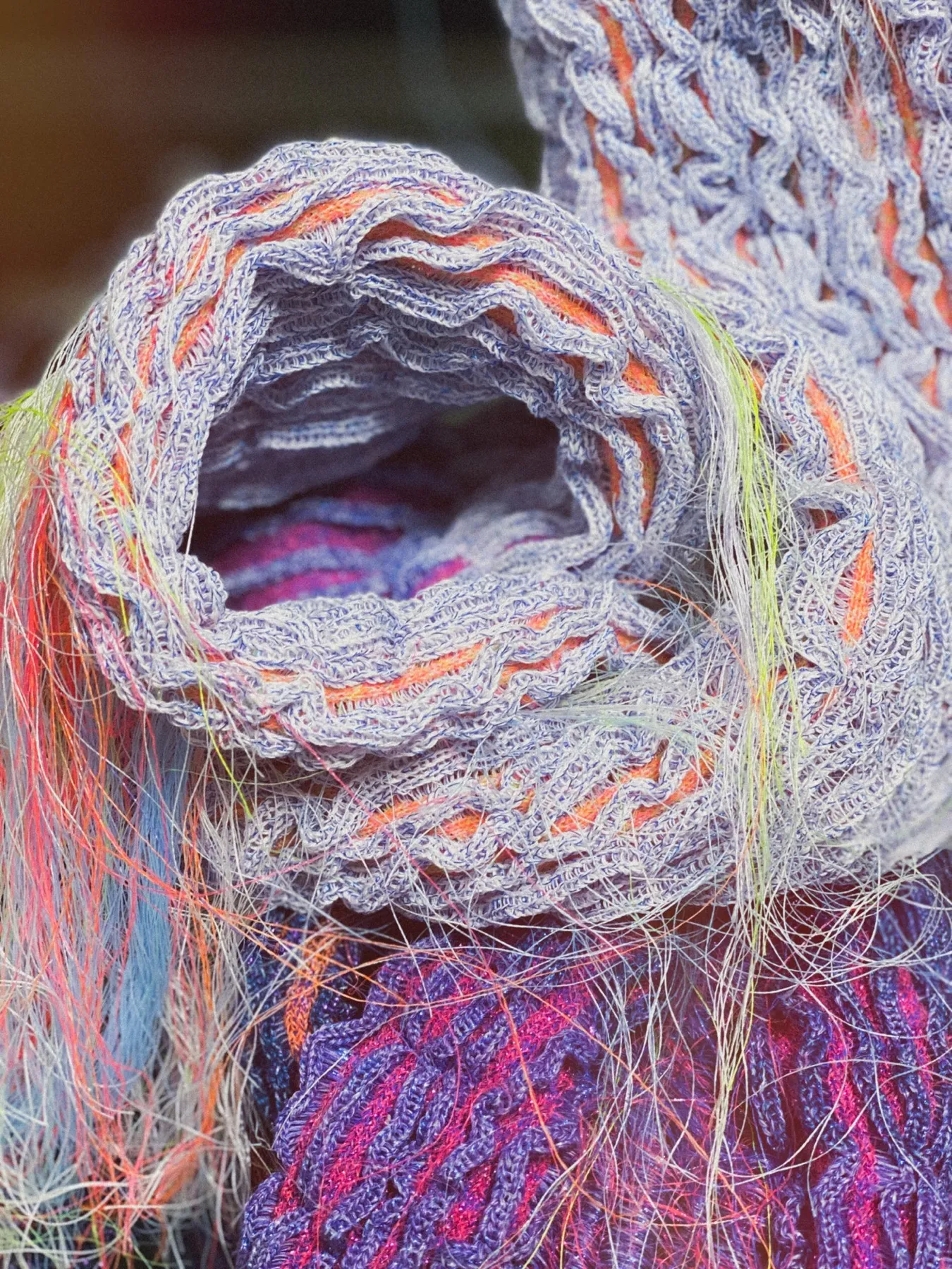Detalj ur Flora Kraft — rullad stickad struktur i ljuslila med orange och neongröna trådar, Amandah L'Narte