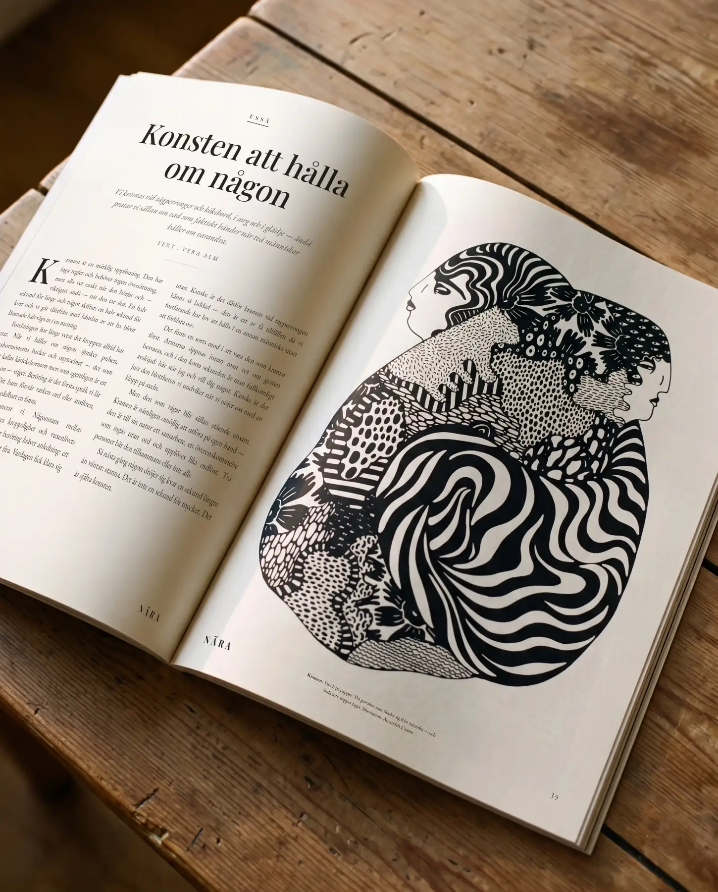 A mock-up of a fictional magazine spread on a wooden table pairs the essay Konsten att hålla om någon with the illustration Kramen: two ink-drawn figures turn their faces away from each other yet remain held in a close embrace of swirling stripes, flowers and dots.