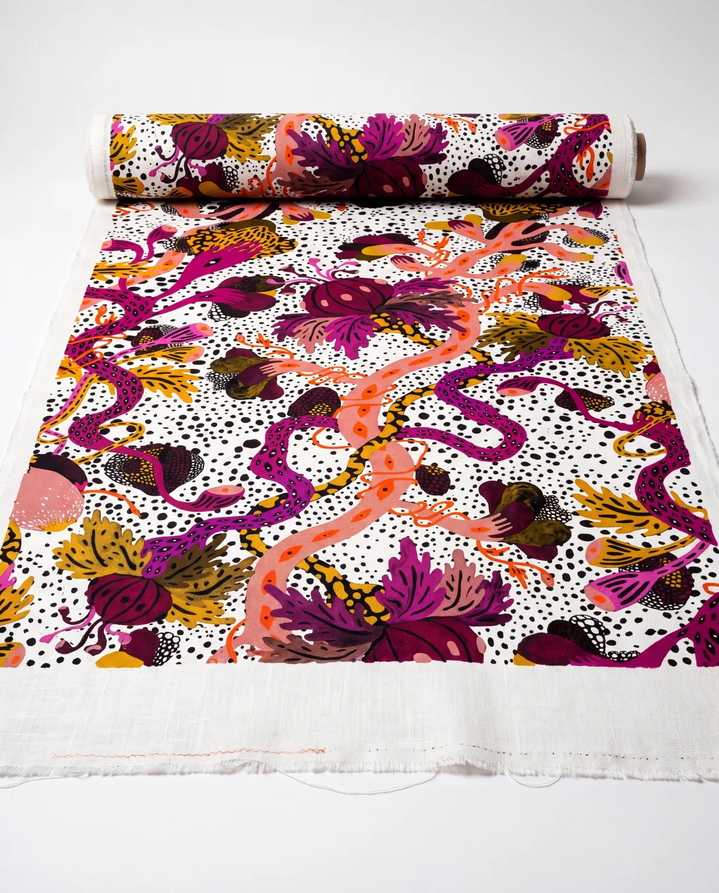 A visualisation presents the pattern on a partly unrolled length of fabric, with magenta flowers, ochre foliage and coral-pink tendrils across a densely dotted ground.