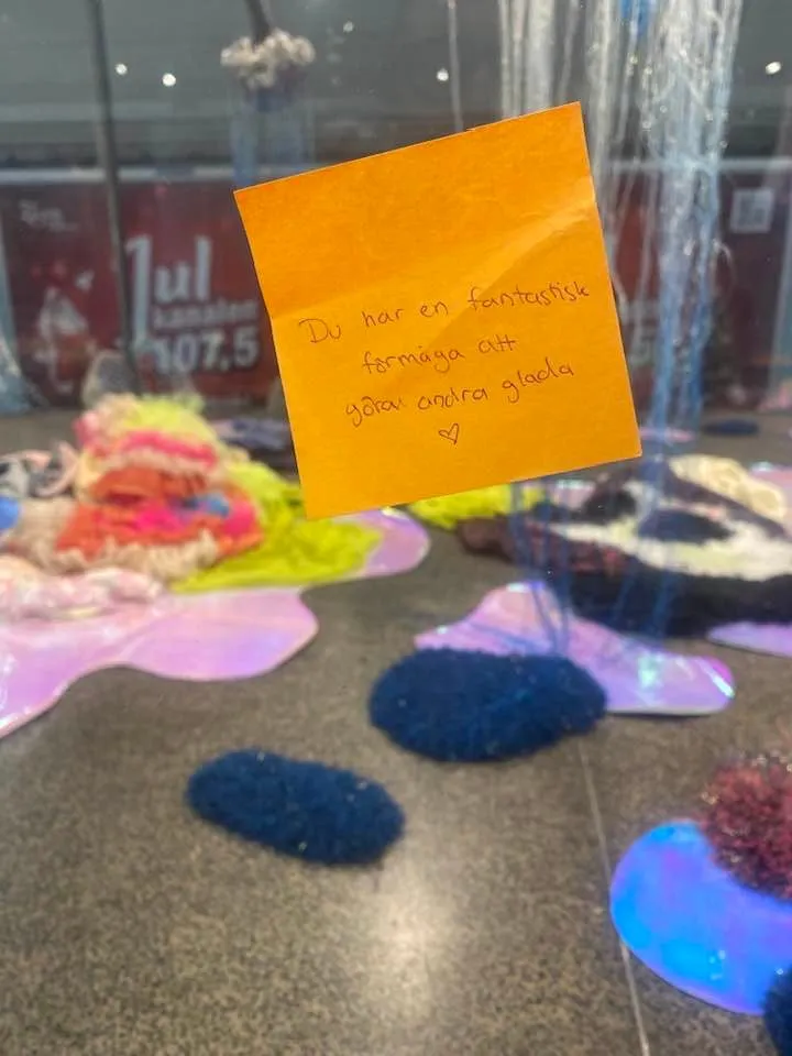 En orange post-it-lapp fäst på monterglaset med en handskriven hälsning från en besökare: Du har en fantastisk förmåga att ge andra glädje, med ett hjärta under